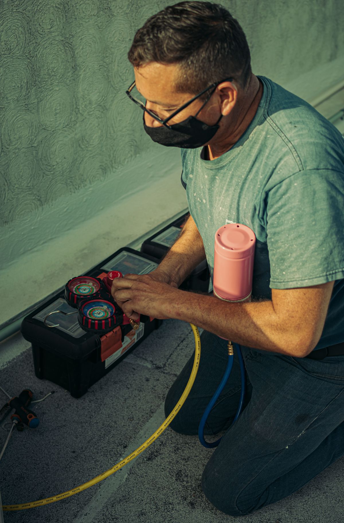 HVAC technician kneeling beside an outdoor unit performing maintenance